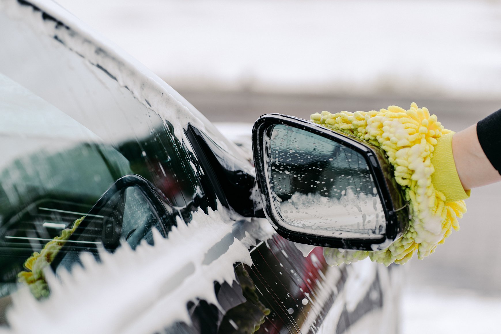 Hand of Man Holding Yellow Sponge Washing Car Side Window with Foam on Cleaning Service. Cleanliness of Automobile. Detailed Vehicle Cleaning